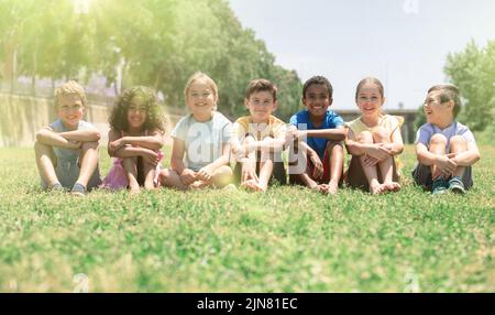 Group of happy kids on green grass in park Stock Photo