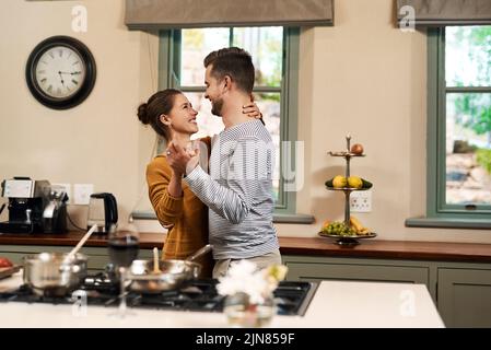 If dancing be the food of love... an affectionate young couple dancing together in their kitchen at home. Stock Photo