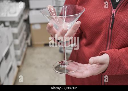 Caucasian girl buys large, transparent glass for martinis and cocktails in store Stock Photo