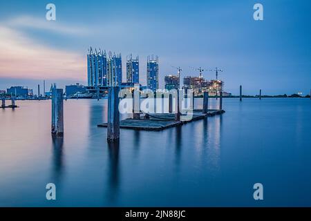 The skyline of Jakarta viewed from the bay with wood pilings, Indonesia Stock Photo