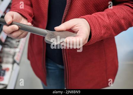 Woman in building materials store chooses for buy wide drill for drilling walls Stock Photo