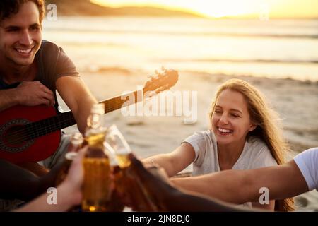 Heres to summer and great friends. a group of friends enjoying drinks on the beach. Stock Photo