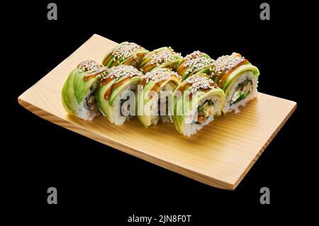 The Green Dragon roll is laid out on a wooden stand on a black isolated background Stock Photo