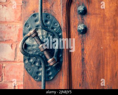 Old metal doorknob on the old wooden door, selective focus. Vintage forged padlock and door handle, close up Stock Photo