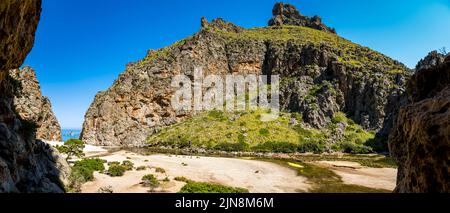 Panorama view to the mediterranean sea of a valley inside the deep gorge with riverbank of Torrent de Pareis mountain stream and Cala de Sa Calobra. Stock Photo