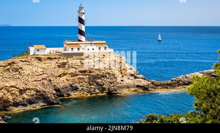 Panorama view of the Mallorca Cala Figuera lighthouse on a peninsula with sailboat in front of the mediterranean sea and cape Cap Blanc. Stock Photo