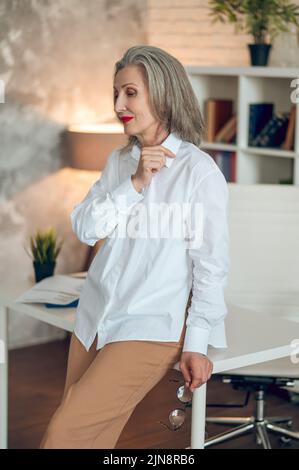 A woman standing in the office, feeling bad and looking tired Stock Photo