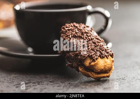 Petit fours with chocolate sprinkles. Mini chocolate dessert and a coffee cup. Stock Photo