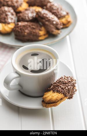 Petit fours with chocolate sprinkles. Mini chocolate dessert and a coffee cup. Stock Photo
