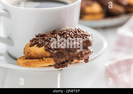 Petit fours with chocolate sprinkles. Mini chocolate dessert and a coffee cup. Stock Photo