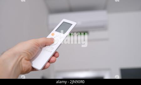 Operation of the air conditioner from remote control in hand Stock Photo
