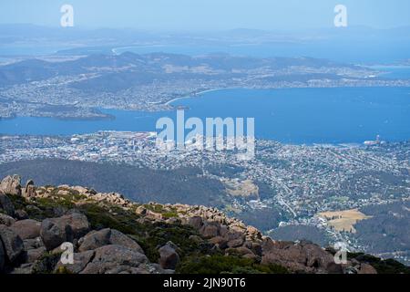 An aerial view of a town against a blue sea seen from a mountain in Tasmania Stock Photo