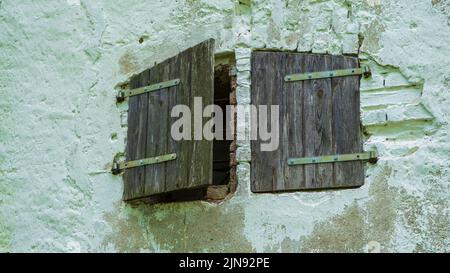 Concrete brick wall and small windows of an abandoned old building exterior. Stock Photo