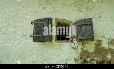 Concrete brick wall and small windows of an abandoned old building exterior. Stock Photo