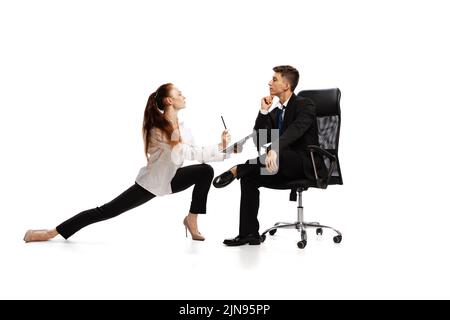 Co-workers. Two stylish office workers in business suits in action isolated on white background. Art, beauty, fashion and business concept Stock Photo