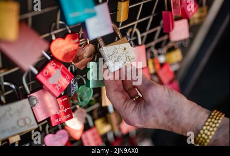 Heilbronn, Germany. 10th Aug, 2022. On the 'Day of the Love Lock' in Heilbronn, Ingrid Hey shows her love lock at the Götzenturm Bridge regarding the diamond wedding with her husband Hans Hey. More than a decade ago, initiator Hans Hey and his wife were the first to put up a love lock on the railing of the Götzenturm bridge to mark their golden wedding anniversary - Today, around 15,000 locks hang there. Credit: Christoph Schmidt/dpa/Alamy Live News Stock Photo