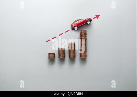 Increasing petrol price concept, business chart stacks of coins with toy car moving upwards Stock Photo