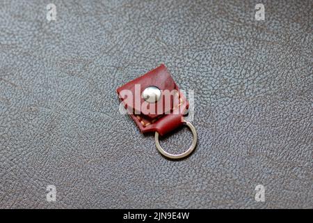 Orange leather key strap with iron ring for mounting on a belt on a leather background. Back side. Stock Photo