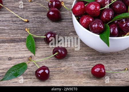 Ripe cherry in water drops on a wooden background, close-up Stock Photo