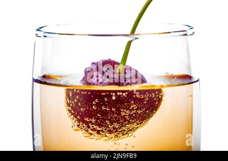 Cherry in a champagne glass, covered with gas bubbles, macro photography Stock Photo
