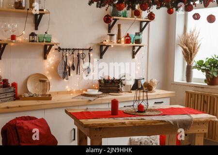The kitchen is decorated in a Christmas style with red accents. Cozy atmosphere of winter holidays. Stock Photo