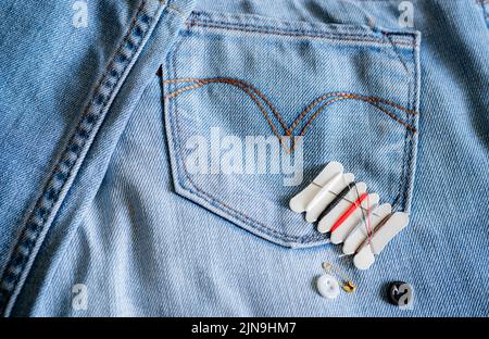 Hotel sewing kit on jeans. Small portable thread repair emergency kit with needles, buttons, threads, and safety pins for hotel, home, and travel. Eco Stock Photo
