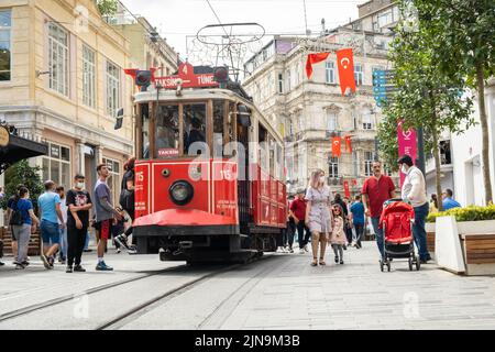 Istanbul, Turkey - September, 6, 2021: Red retro tram on famous tourist and shopping street Istiklal among crowd of people Stock Photo