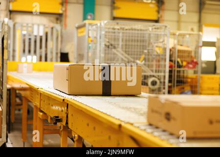 Box on conveyor roller. Delivery service, distribution warehouse and parcels transportation system. Stock Photo