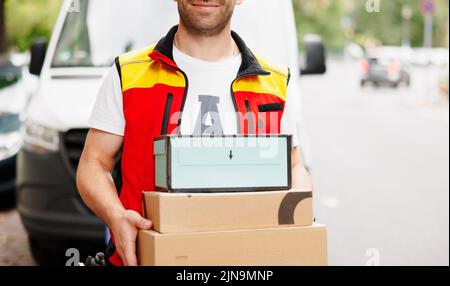 Delivery man holding pile of cardboard boxes in front. Stock Photo