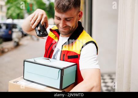 Delivery man scanning boxes a barcode packages with a handheld barcode scanner Stock Photo