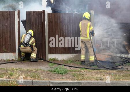 Essex Fire and Rescue Service firefighters in protective clothing dangerous & hazardous work on house fire working with breathing apparatus England UK Stock Photo