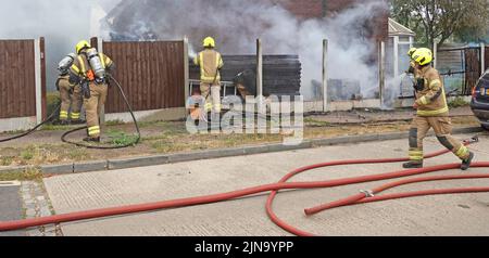 Essex Fire and Rescue Service firefighters in protective clothing dangerous & hazardous work on house fire working with breathing apparatus England UK Stock Photo