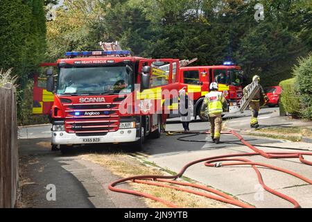 Essex fire and rescue service fire brigade firemen attending house fire with two fire engines & firefighters in residential street England UK Stock Photo