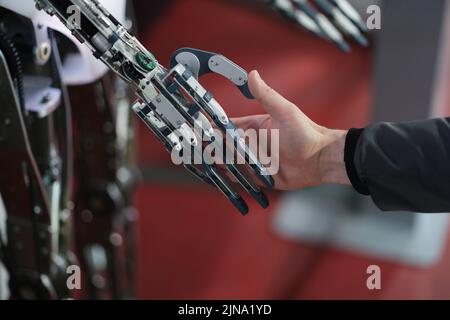 Robot extends its hand to man for handshake Stock Photo