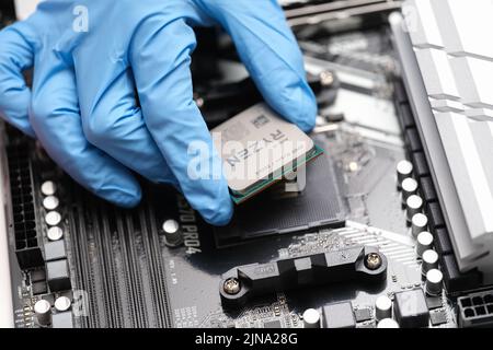 Tbilisi, Georgia - July 26, 2022: Installation of third generation Ryzen processor on motherboard Stock Photo