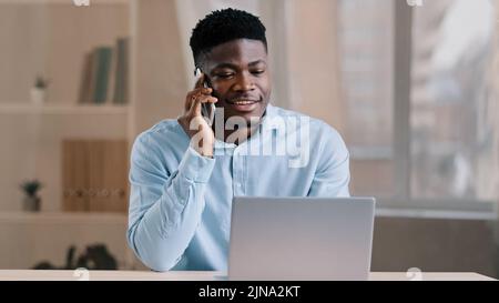 African american man businessman freelancer worker talk chatter on mobile cellphone with client make business call discussion listen news explain Stock Photo