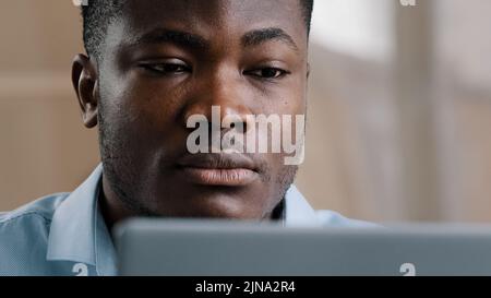 Serious male young african american businessman programmer typing on computer at home office focused concentrated millennial confident guy use laptop Stock Photo