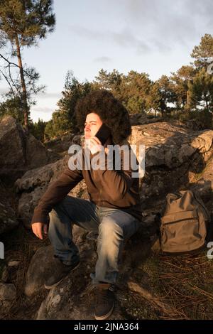 man with afro style hair sitting speaks on the phone Stock Photo