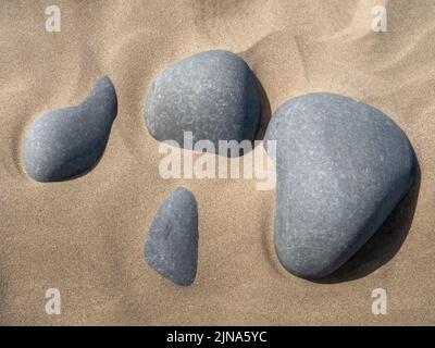 Grey pebbles on golden sandy beach, abstract effect image. Stock Photo