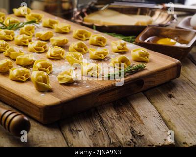 Homemade ravioli, dumplings stuffed with minced meat on a cutting board, wooden background. The process of making homemade dumplings, ravioli. Stock Photo