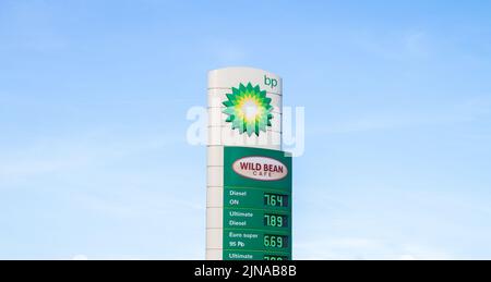 BP petrol station and Wild Bean Cafe. British Petroleum oil company gas station, forecourt pylon with logo and prices displayed. Stock Photo