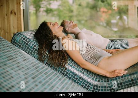 Handsome young couple relaxing on the tepidarium bed in the spa Stock Photo