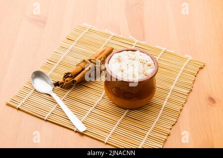 Rice pudding in a clay glass with some cinnamon sticks and a spoon. Stock Photo