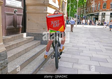 Just Eat fast food sign logo on back of rucksack on cyclist man courier delivery bike  in Cardiff City street Wales UK   KATHY DEWITT Stock Photo