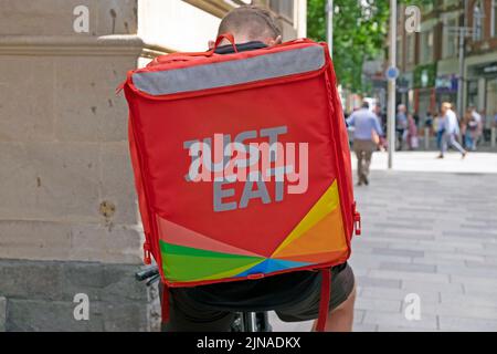 Just Eat fast food sign logo on back of rucksack on cyclist man courier delivery bike  in Cardiff City street Wales UK   KATHY DEWITT Stock Photo