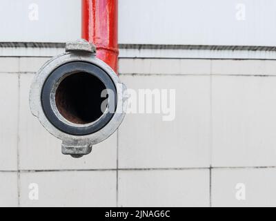 Red fire-fighting pipeline with a lock close-up on a tile background Stock Photo