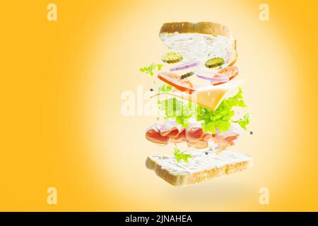 Colorful composition. On a sunny yellow background, an appetizing sandwich with meat, vegetables and herbs in a frozen flight. Restaurant, cafe, cante Stock Photo