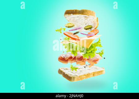 American burger with minced meat, fresh vegetables, herbs and cheese in a frozen flight on a turquoise background. Light snack, picnic, banquet, holid Stock Photo