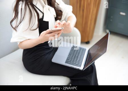 A Japanese woman checking smartphone in the home office faceless composition Stock Photo