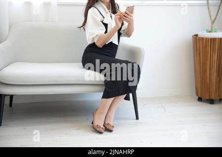 A Japanese woman checking smartphone in the home office faceless composition Stock Photo